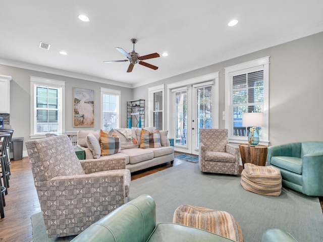 living room featuring wood-type flooring, ceiling fan, and crown molding