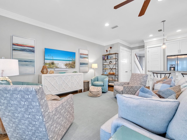 living room featuring ceiling fan, light colored carpet, and ornamental molding