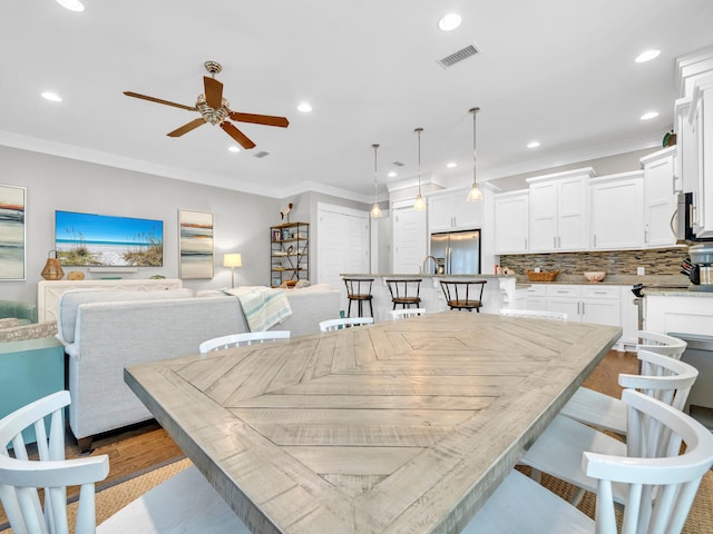 dining area with light wood-type flooring, ceiling fan, and ornamental molding