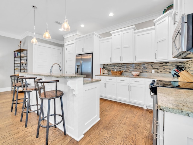 kitchen featuring white cabinetry, an island with sink, pendant lighting, and appliances with stainless steel finishes