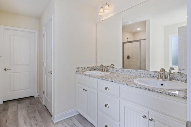 bathroom with hardwood / wood-style floors, vanity, and a shower with shower door