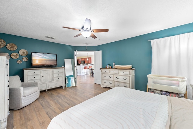 bedroom with ceiling fan, wood-type flooring, and a textured ceiling