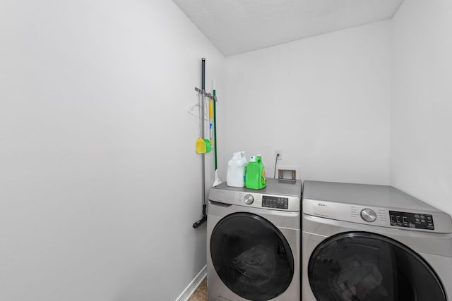 clothes washing area featuring washing machine and clothes dryer and a textured ceiling