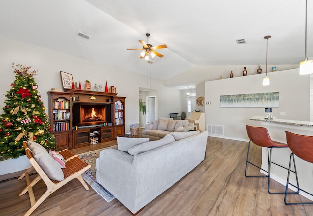 living room featuring ceiling fan, wood-type flooring, and vaulted ceiling