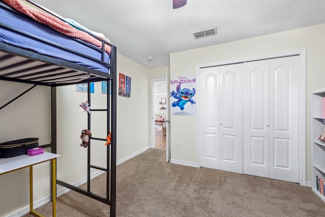 bedroom featuring carpet, ceiling fan, a textured ceiling, and a closet