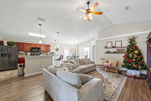 living room featuring a textured ceiling, dark hardwood / wood-style flooring, ceiling fan with notable chandelier, and lofted ceiling