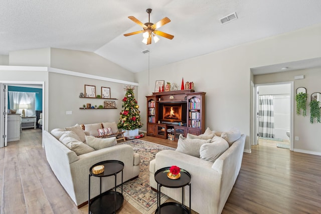 living room featuring hardwood / wood-style floors, a textured ceiling, ceiling fan, and lofted ceiling