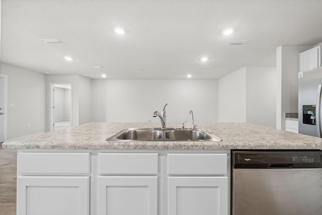 kitchen featuring a center island with sink, sink, light wood-type flooring, appliances with stainless steel finishes, and white cabinetry