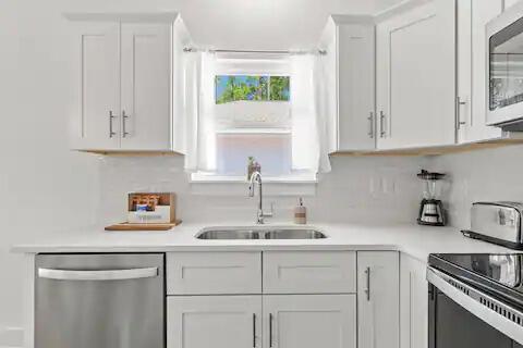 kitchen featuring white cabinets, decorative backsplash, sink, and appliances with stainless steel finishes