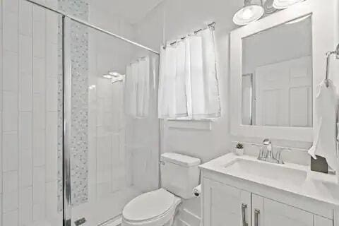 bathroom featuring a tile shower, vanity, and toilet