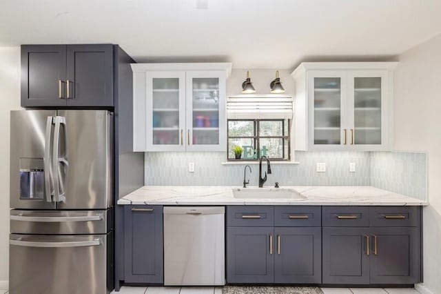 kitchen featuring light stone counters, stainless steel appliances, white cabinetry, and sink