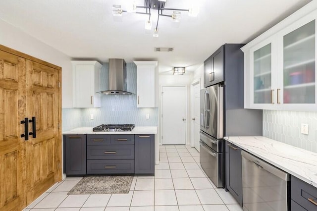 kitchen with white cabinetry, wall chimney exhaust hood, stainless steel appliances, tasteful backsplash, and light tile patterned floors