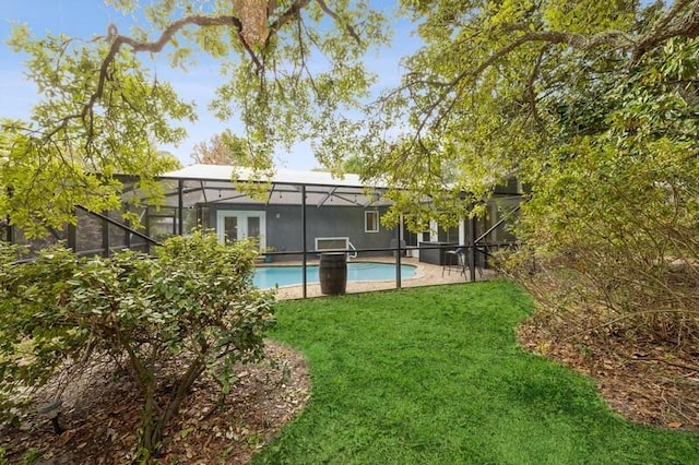 rear view of house featuring a lawn, a patio area, and a lanai