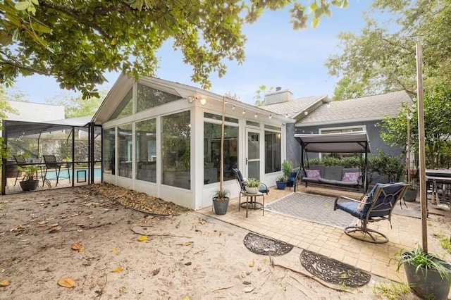 back of house featuring a sunroom, a patio, and an outdoor living space