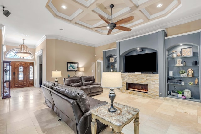 living room featuring ornamental molding, a stone fireplace, built in shelves, and coffered ceiling