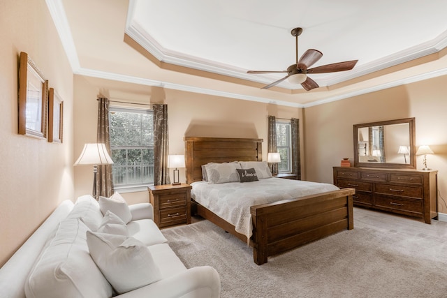 bedroom with a tray ceiling, ceiling fan, crown molding, and light carpet