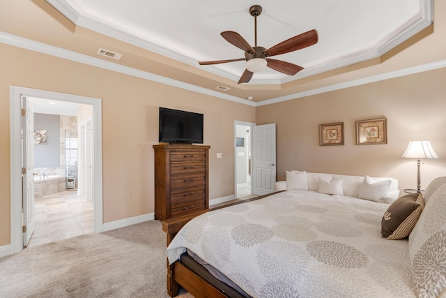 bedroom featuring light carpet, ornamental molding, a tray ceiling, ceiling fan, and connected bathroom