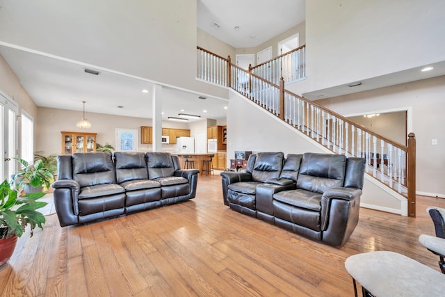 living room with a towering ceiling, french doors, and light hardwood / wood-style flooring