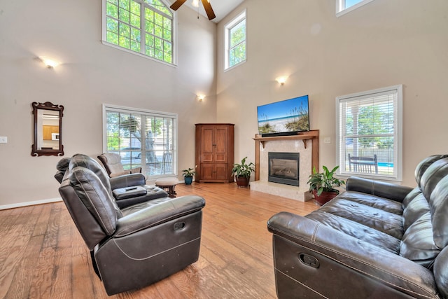 living room with a towering ceiling, a tile fireplace, and a healthy amount of sunlight