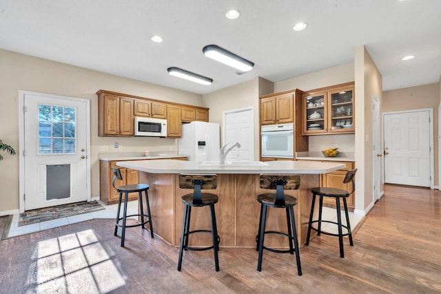 kitchen with white appliances, a kitchen breakfast bar, a large island, and hardwood / wood-style flooring