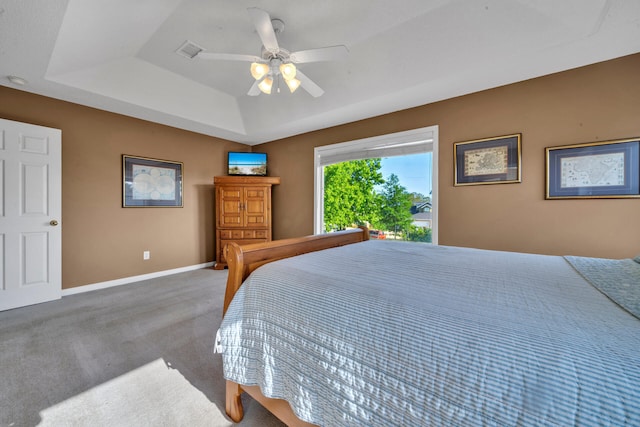 carpeted bedroom featuring a raised ceiling and ceiling fan