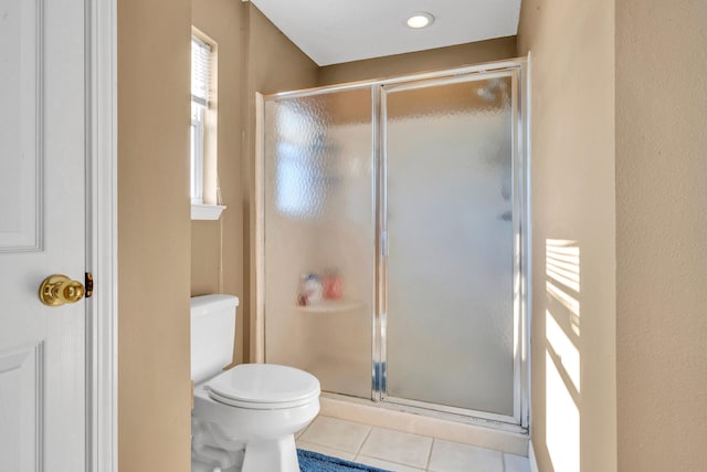 bathroom featuring toilet, an enclosed shower, and tile patterned flooring