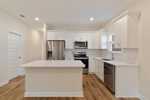 kitchen with light wood-type flooring, a center island, stainless steel appliances, and sink