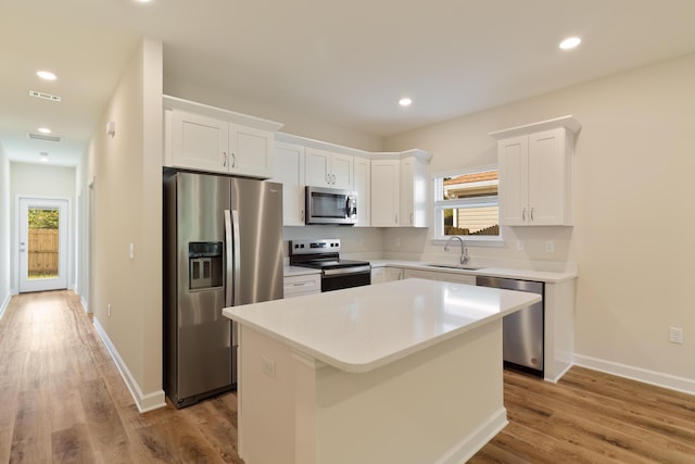 kitchen with a center island, sink, light wood-type flooring, appliances with stainless steel finishes, and white cabinetry