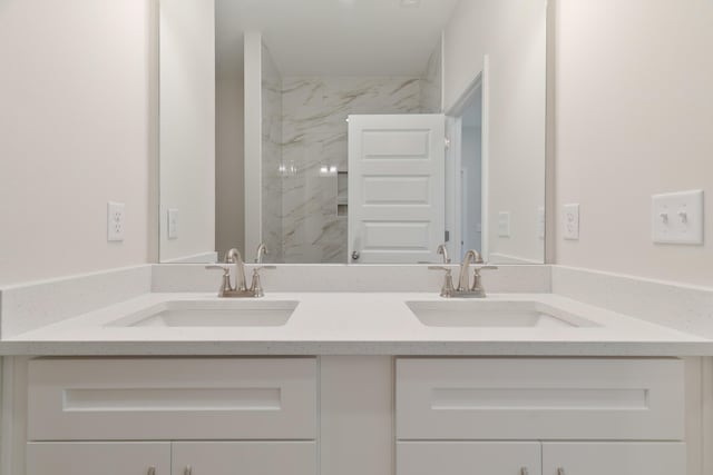 bathroom with a tile shower and vanity