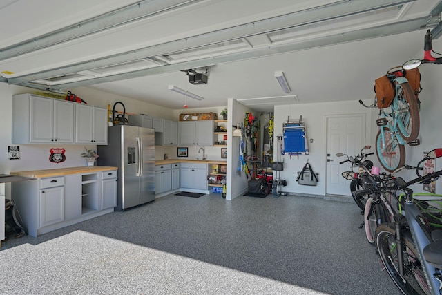 garage featuring stainless steel fridge with ice dispenser and sink