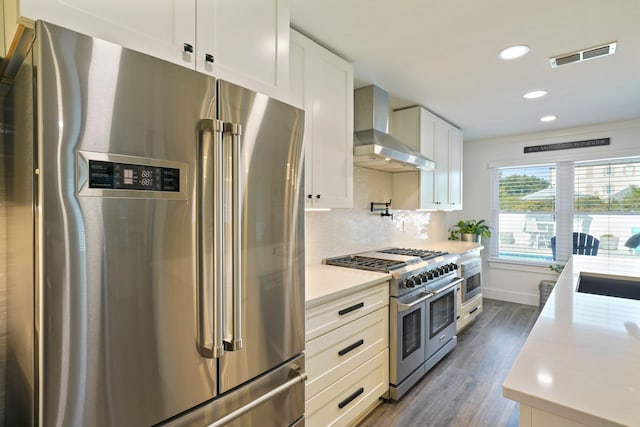 237 Sandy Cay Dr, Miramar Beach, FL 32550 - kitchen featuring stainless steel appliances, wall chimney exhaust hood, light countertops, dark wood finished floors, and white cabinets