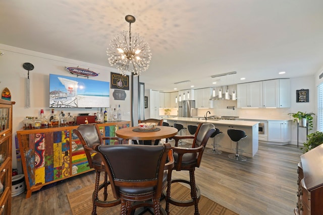 dining room with a notable chandelier, dark wood-type flooring, and sink