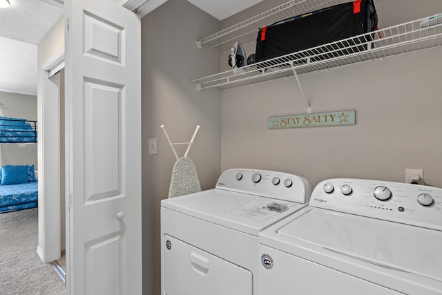 clothes washing area with carpet, washer and dryer, and a textured ceiling