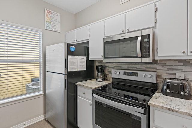 kitchen with white cabinets, decorative backsplash, light stone counters, and appliances with stainless steel finishes