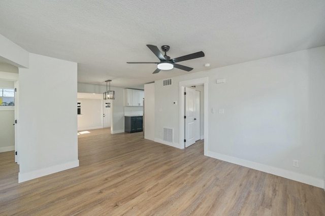 unfurnished living room with ceiling fan, light hardwood / wood-style floors, and a textured ceiling