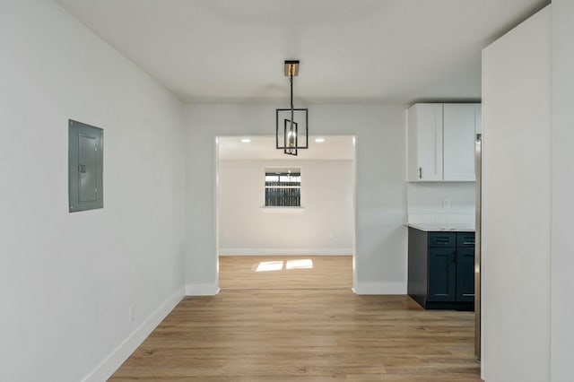 unfurnished dining area featuring electric panel and light hardwood / wood-style flooring