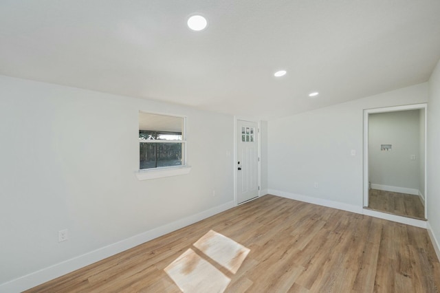 spare room featuring light hardwood / wood-style flooring and vaulted ceiling