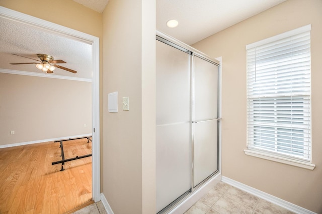 bathroom with hardwood / wood-style floors, a textured ceiling, ceiling fan, and a healthy amount of sunlight