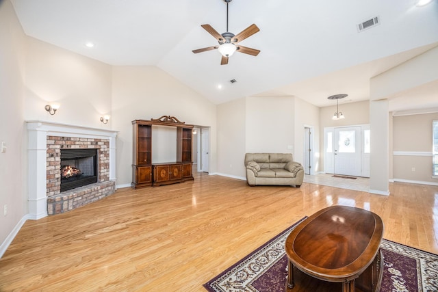 living room featuring a fireplace, ceiling fan, light hardwood / wood-style flooring, and high vaulted ceiling