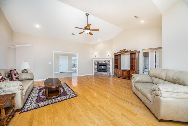 living room with ceiling fan, light hardwood / wood-style floors, a fireplace, and high vaulted ceiling