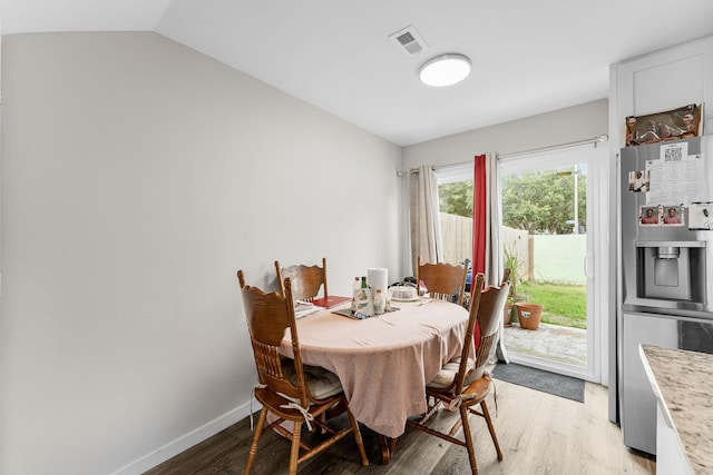 dining room with lofted ceiling and light wood-type flooring