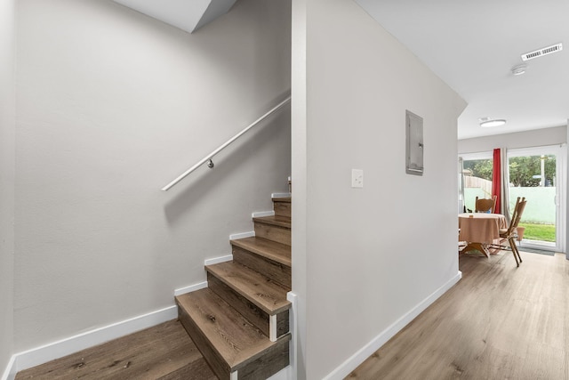 staircase with wood-type flooring and electric panel