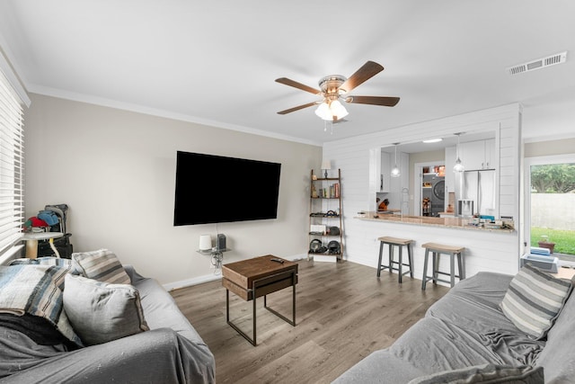 living room with hardwood / wood-style floors, ceiling fan, and ornamental molding