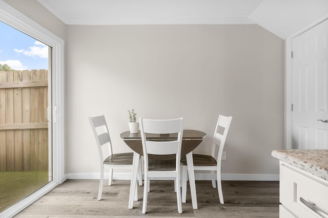 dining room with vaulted ceiling and light hardwood / wood-style flooring