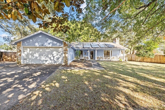 ranch-style home with a front yard, solar panels, a garage, and a porch