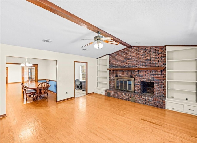 living room with a brick fireplace, lofted ceiling with beams, wood-type flooring, a textured ceiling, and ceiling fan with notable chandelier