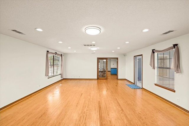 unfurnished living room featuring a textured ceiling and light wood-type flooring