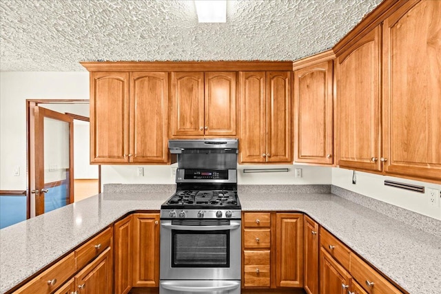 kitchen with light stone counters, stainless steel range with gas cooktop, and a textured ceiling