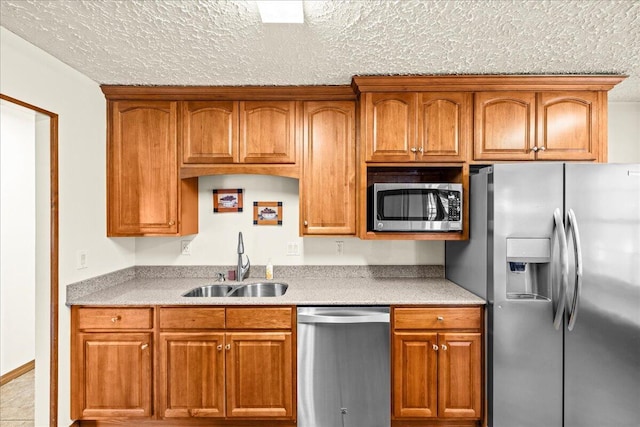 kitchen with appliances with stainless steel finishes, a textured ceiling, and sink