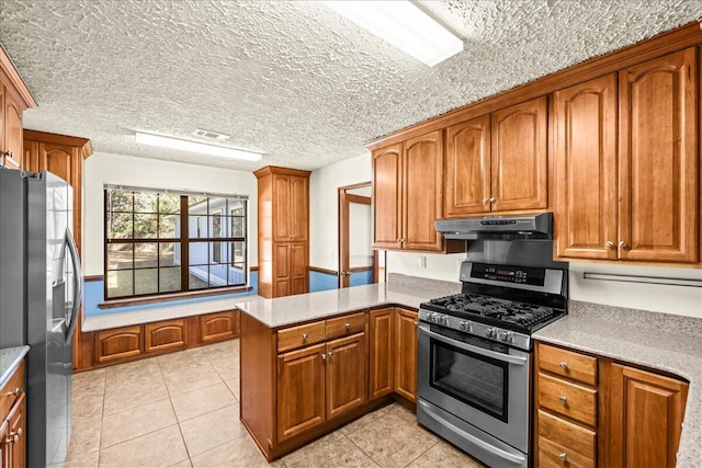 kitchen with kitchen peninsula, light tile patterned flooring, stainless steel appliances, and a textured ceiling